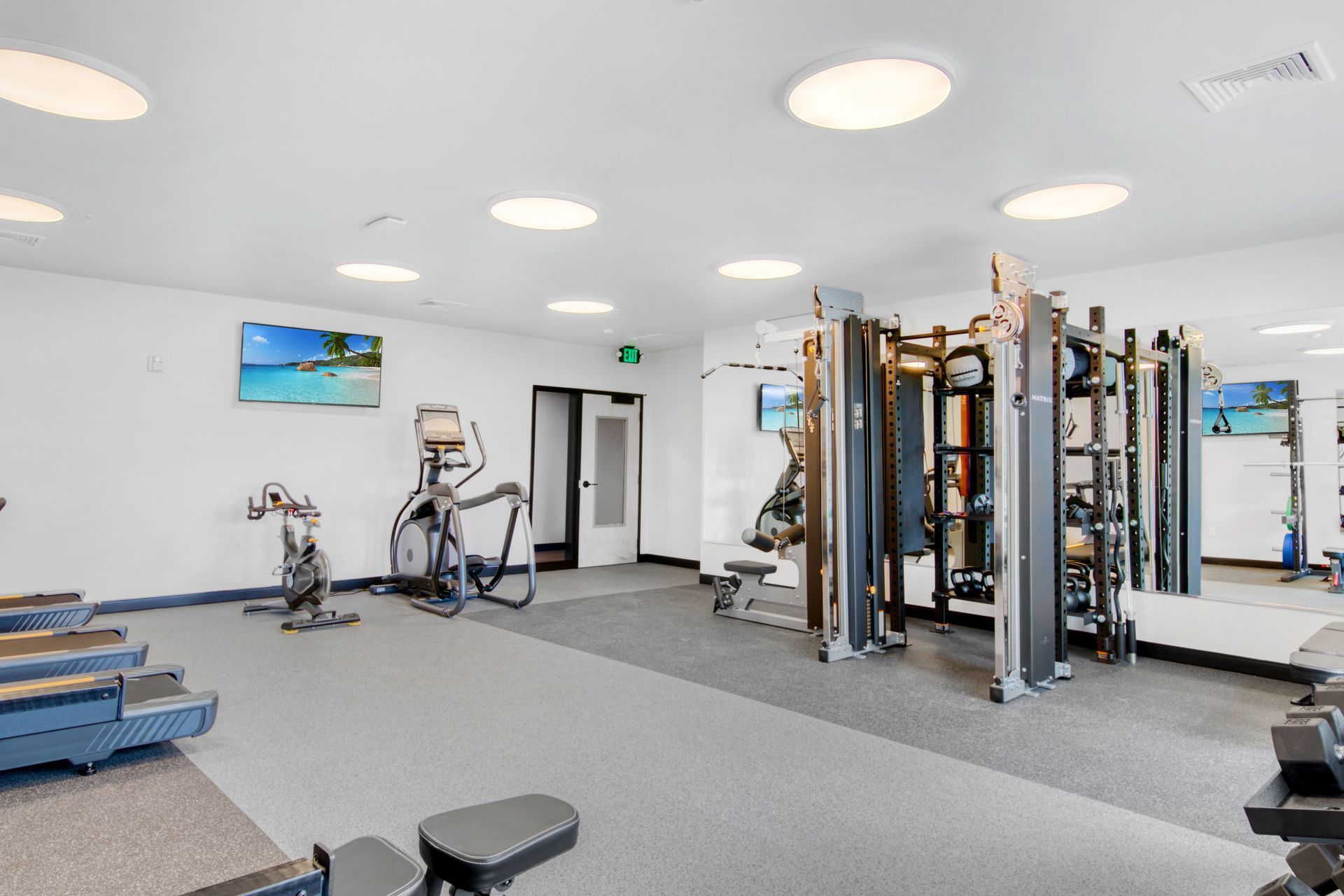 A large gym with a lot of equipment and a large mirror.