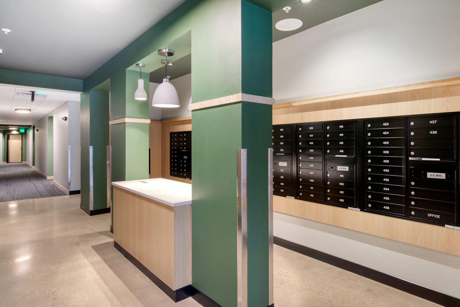A hallway with green walls and black mailboxes