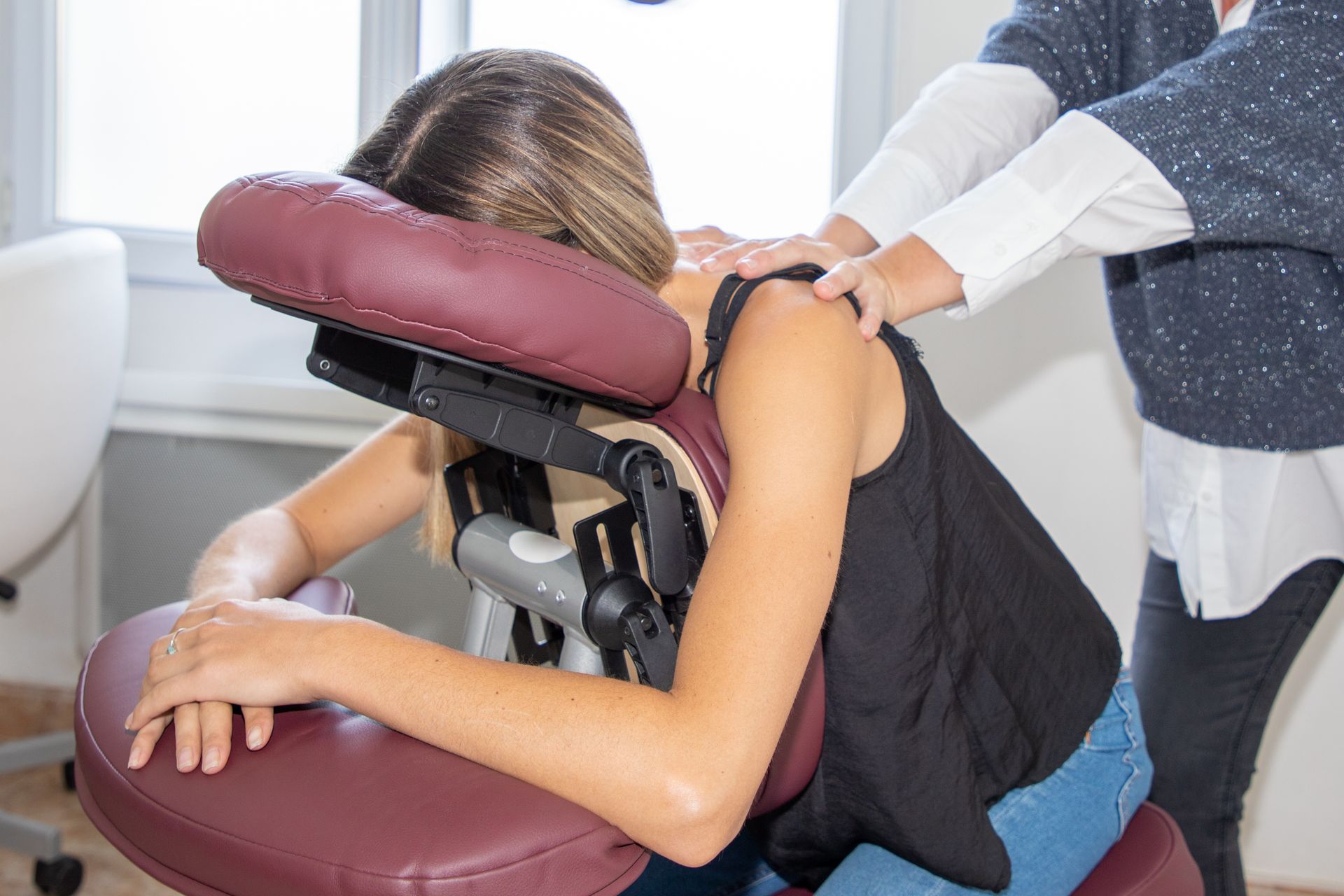 Woman receiving shoulder massage in a massage chair, indoors.
