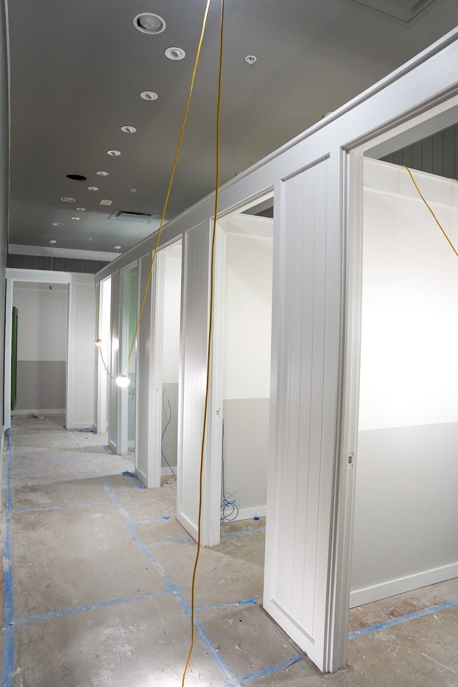 A hallway in a building under construction with white walls and doors.