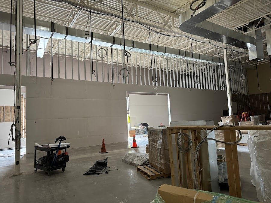 The inside of a building under construction with a lot of wires hanging from the ceiling.