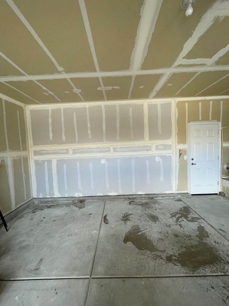 An empty garage with drywall walls and a white door.