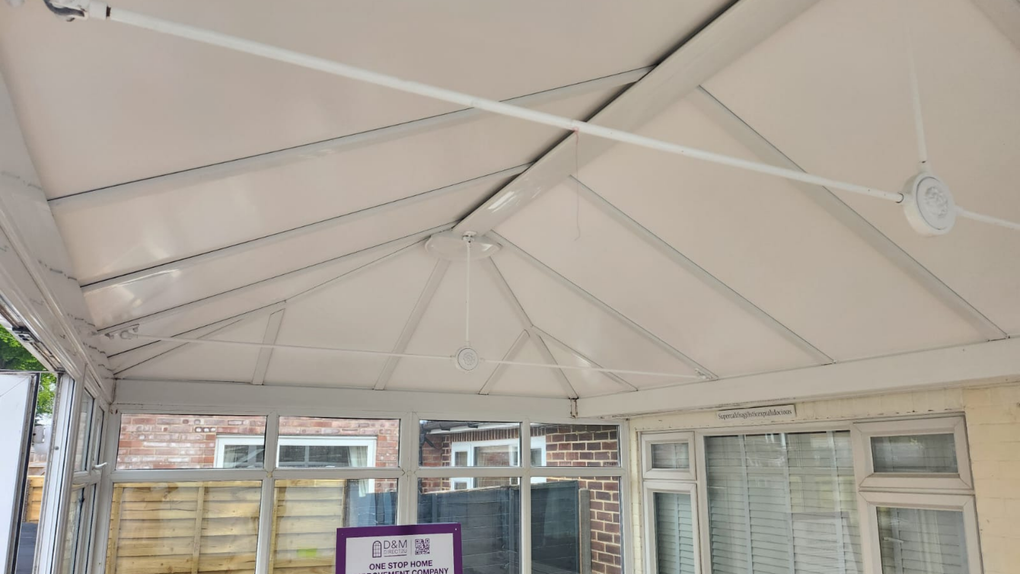 White conservatory ceiling with multiple angled beams and a horizontal support bar.