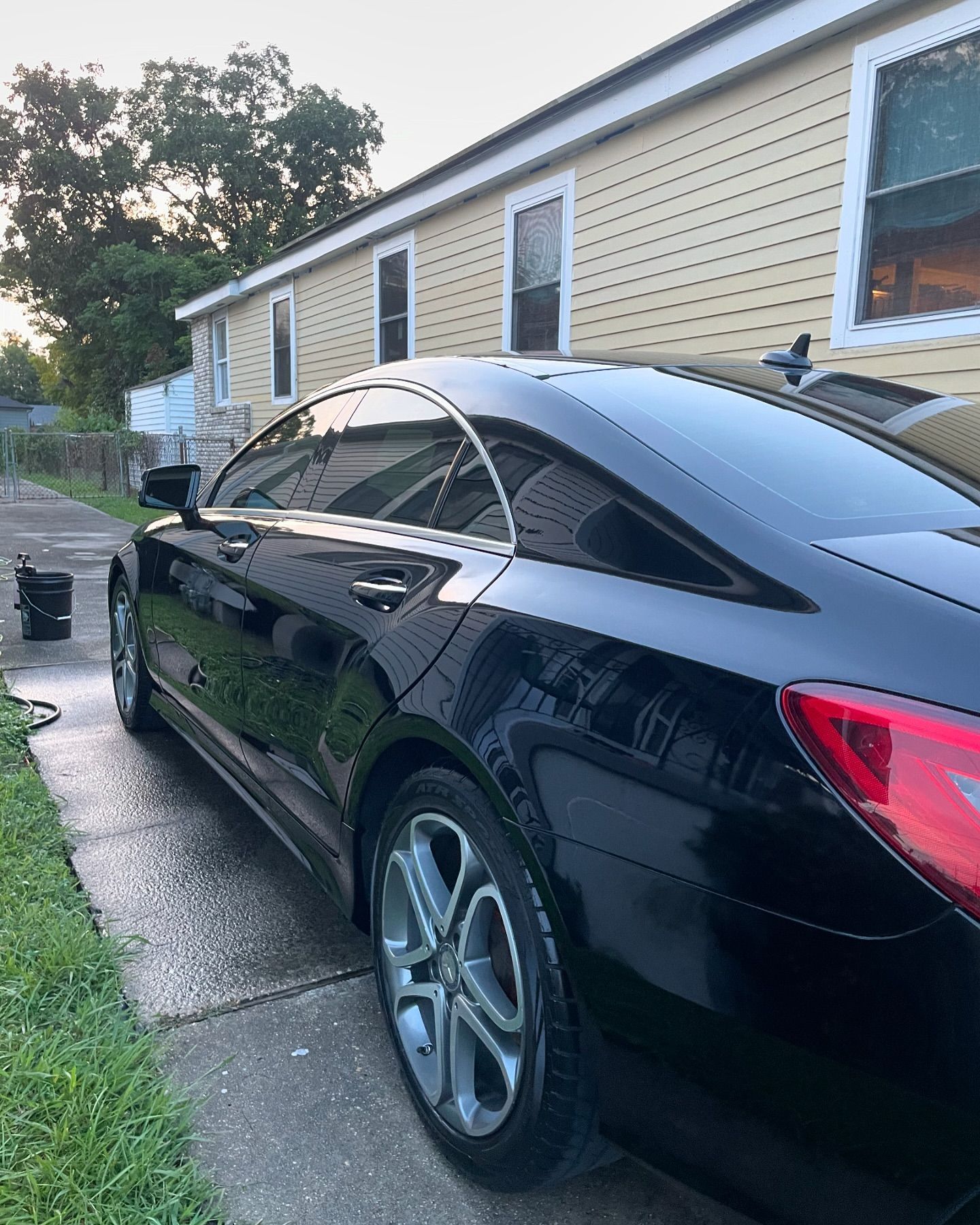 A black car is parked on the side of the road in front of a house.
