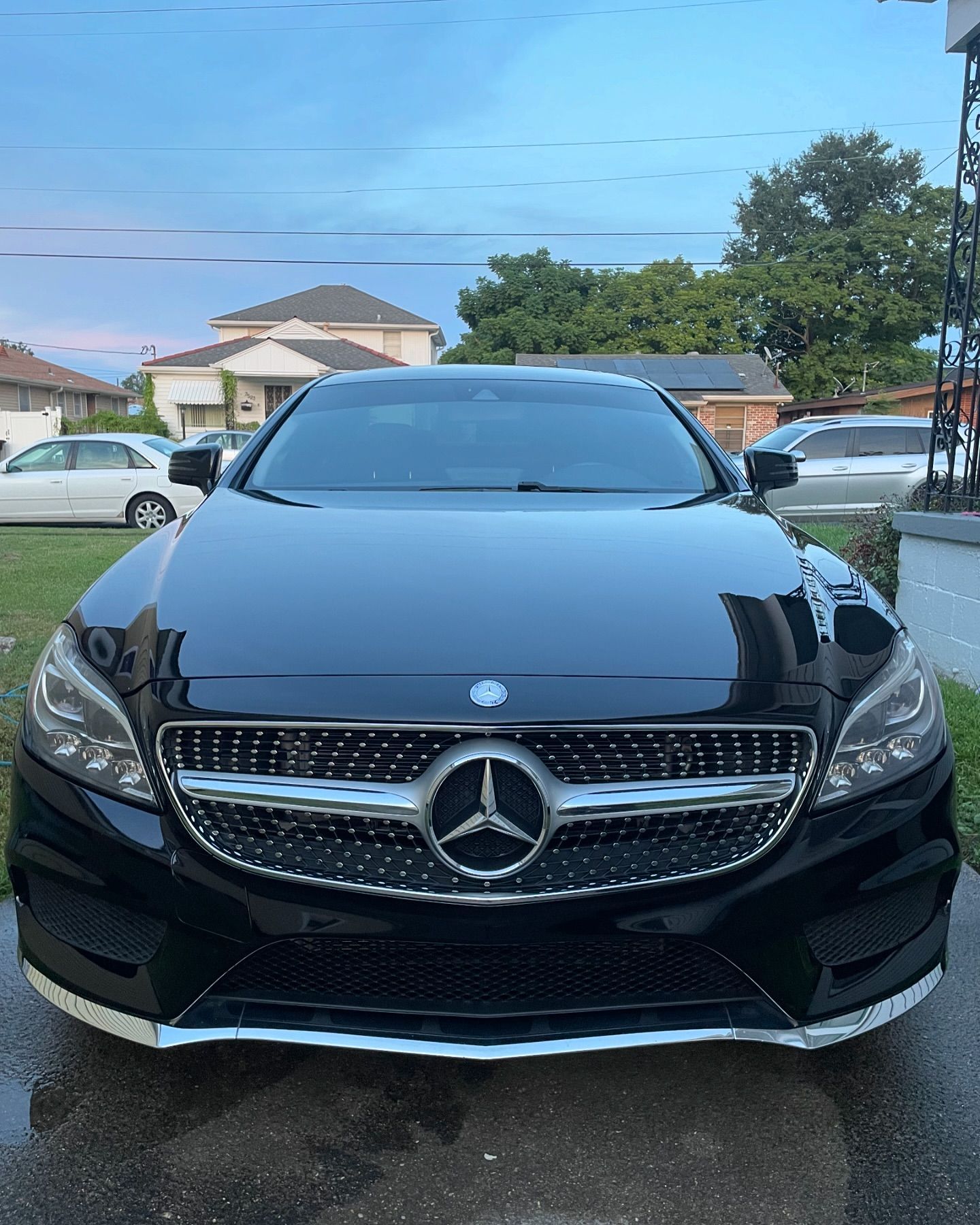 A black mercedes benz is parked in a driveway.