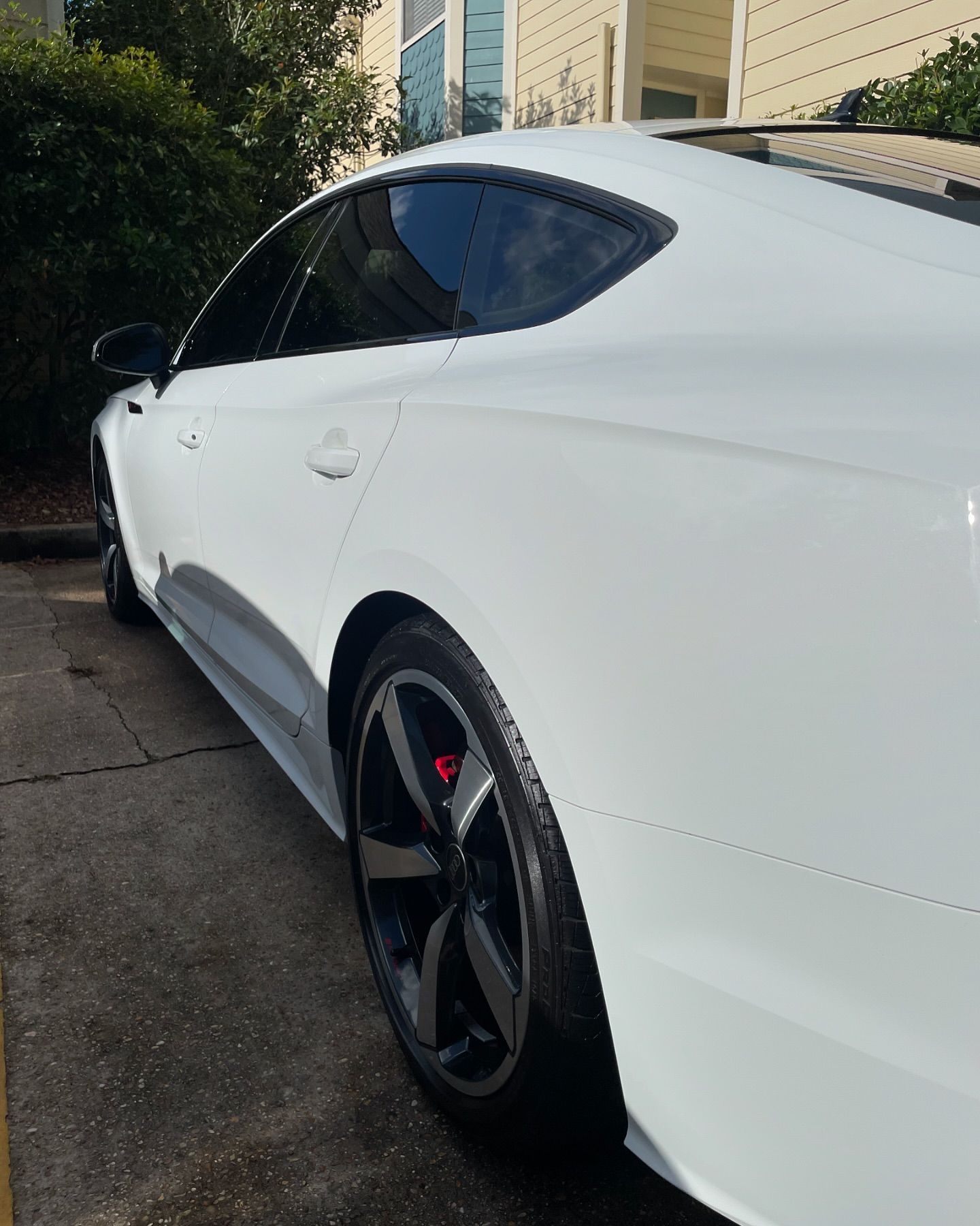 A white car is parked in a driveway in front of a house.