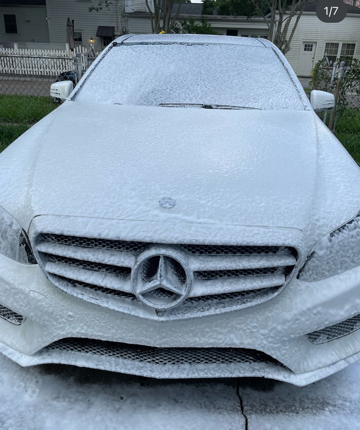 A white mercedes benz car is covered in foam.