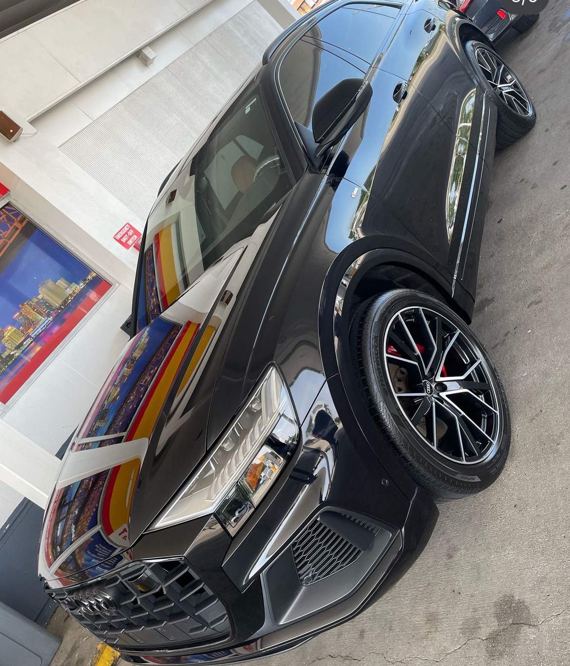 A black car is parked in front of a building