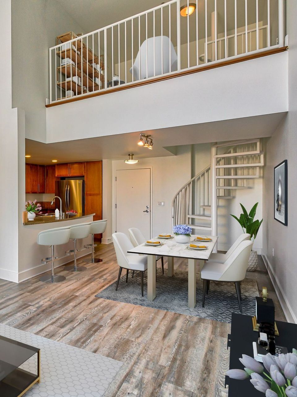 A living room with a dining table and chairs and a spiral staircase