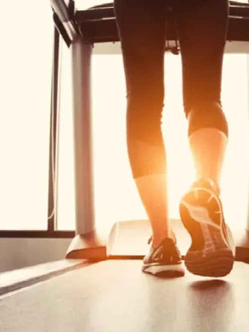 A woman is running on a treadmill in a gym.