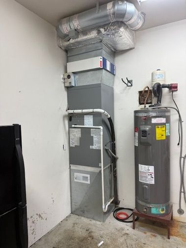 Residential HVAC furnace and water heater in a utility closet with exposed ductwork and pipes