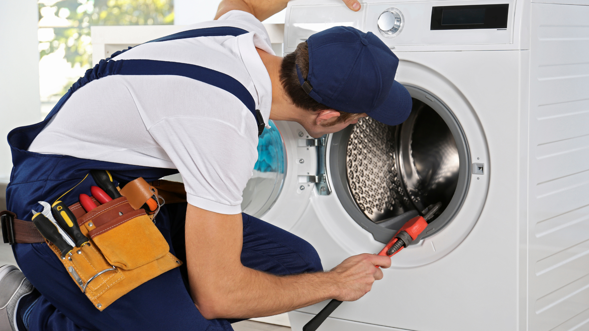 A man is fixing a washing machine with a screwdriver.