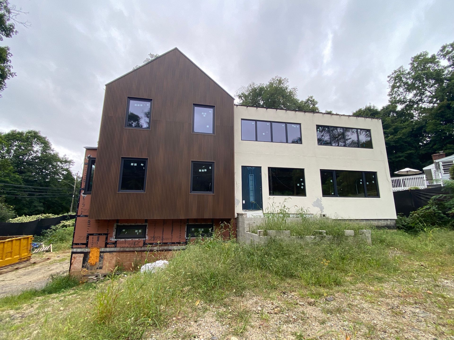 A large house with a lot of windows is being built in a field.