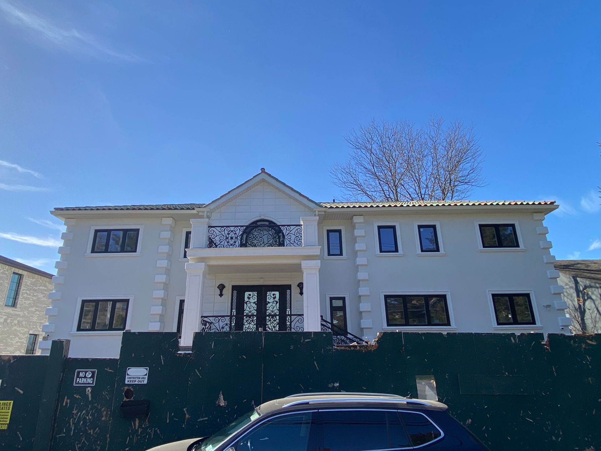 A large white house with a car parked in front of it.