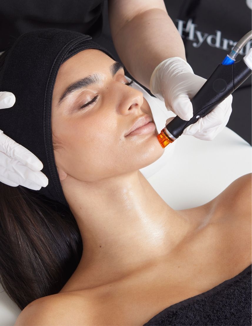 A woman in a black headband is getting a facial treatment