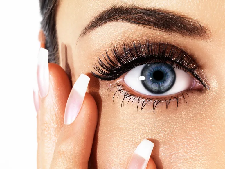 A close up of a woman 's blue eye with long eyelashes.