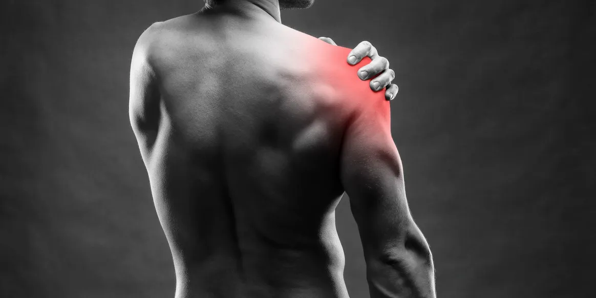 A man is holding his shoulder in pain.