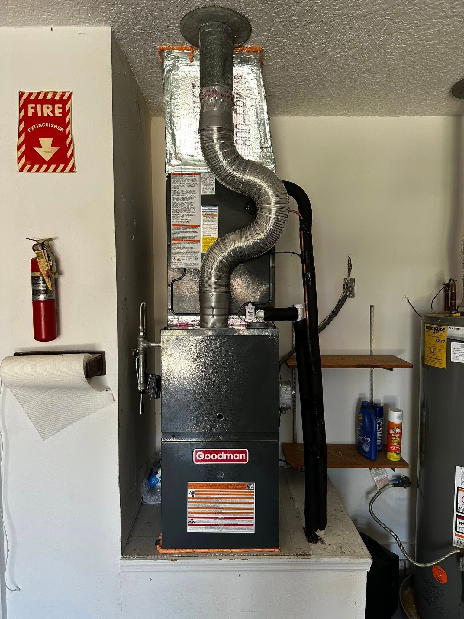 A furnace in a utility closet with a fire extinguisher and water heater nearby.