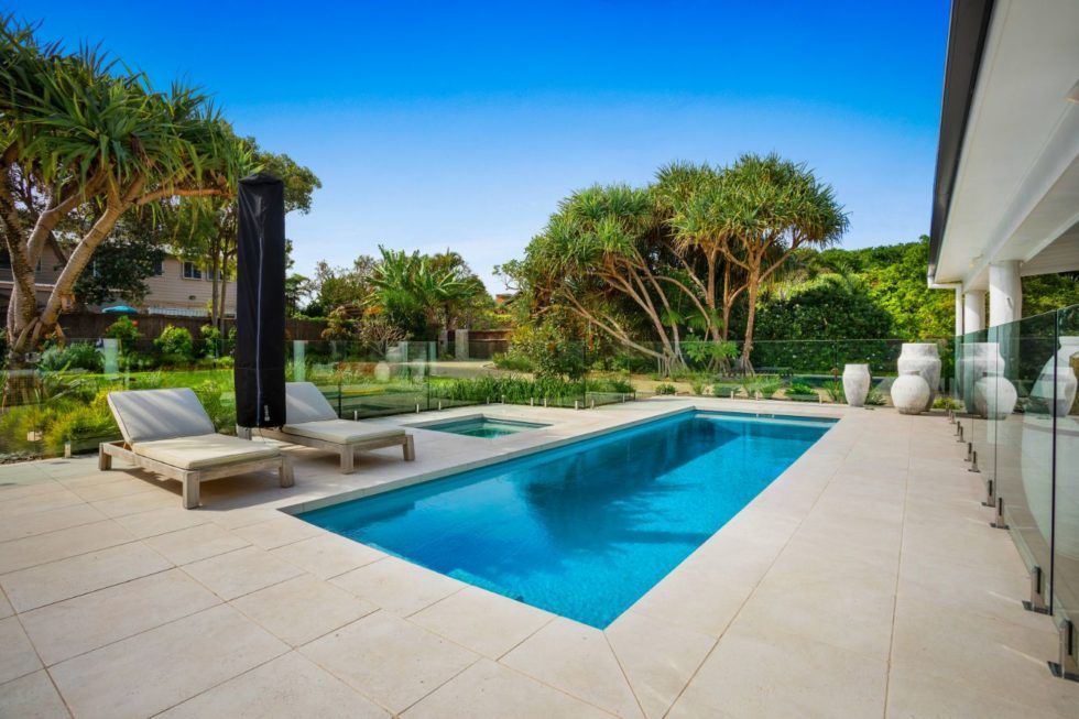 A Large Swimming Pool Is Surrounded By Chairs And Trees — Evoke Pools In Lennox Head, NSW