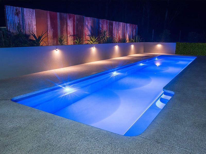 A Large Swimming Pool Is Lit Up At Night — Evoke Pools In Lennox Head, NSW