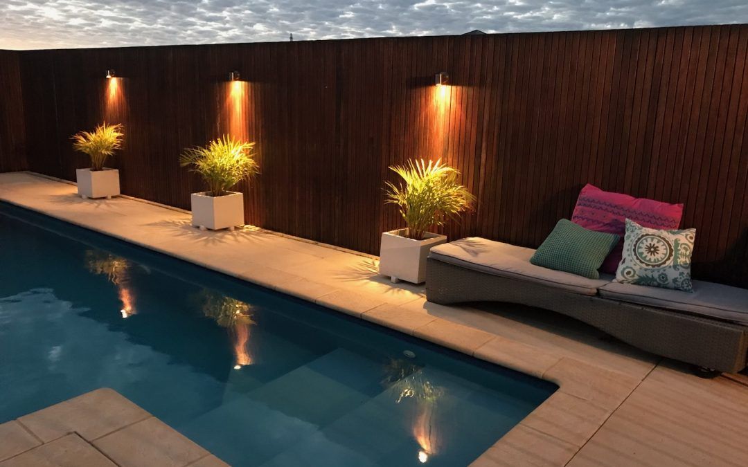 A Swimming Pool With A Wooden Fence Surrounding It — Evoke Pools In Lennox Head, NSW