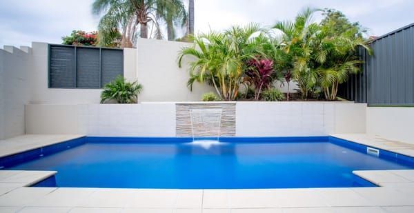 A Large Swimming Pool With A Waterfall In The Backyard Of A House β Evoke Pools In Lennox Head, NSW