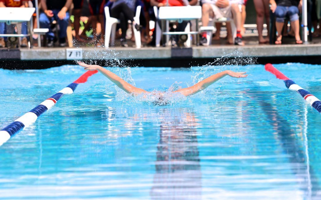 A Person Is Swimming In A Pool With A Crowd Watching — Evoke Pools In Lennox Head, NSW