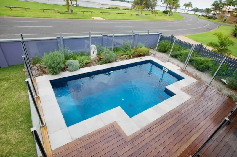 A Small Swimming Pool Is Surrounded By A Fence And A Wooden Deck — Evoke Pools In Lennox Head, NSW