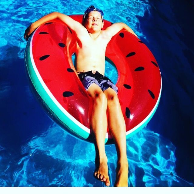 A Boy Is Laying On A Watermelon Float In A Pool — Evoke Pools In Lennox Head, NSW