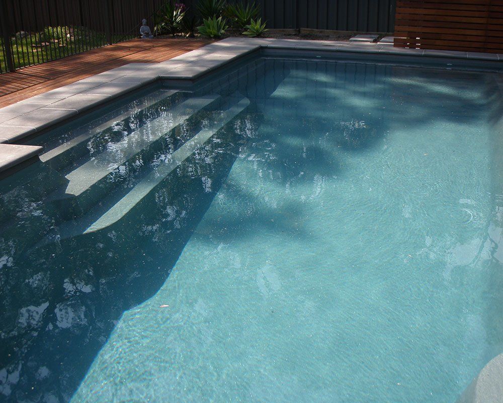 A Swimming Pool With Stairs And A Fence In The Background — Evoke Pools In Lennox Head, NSW