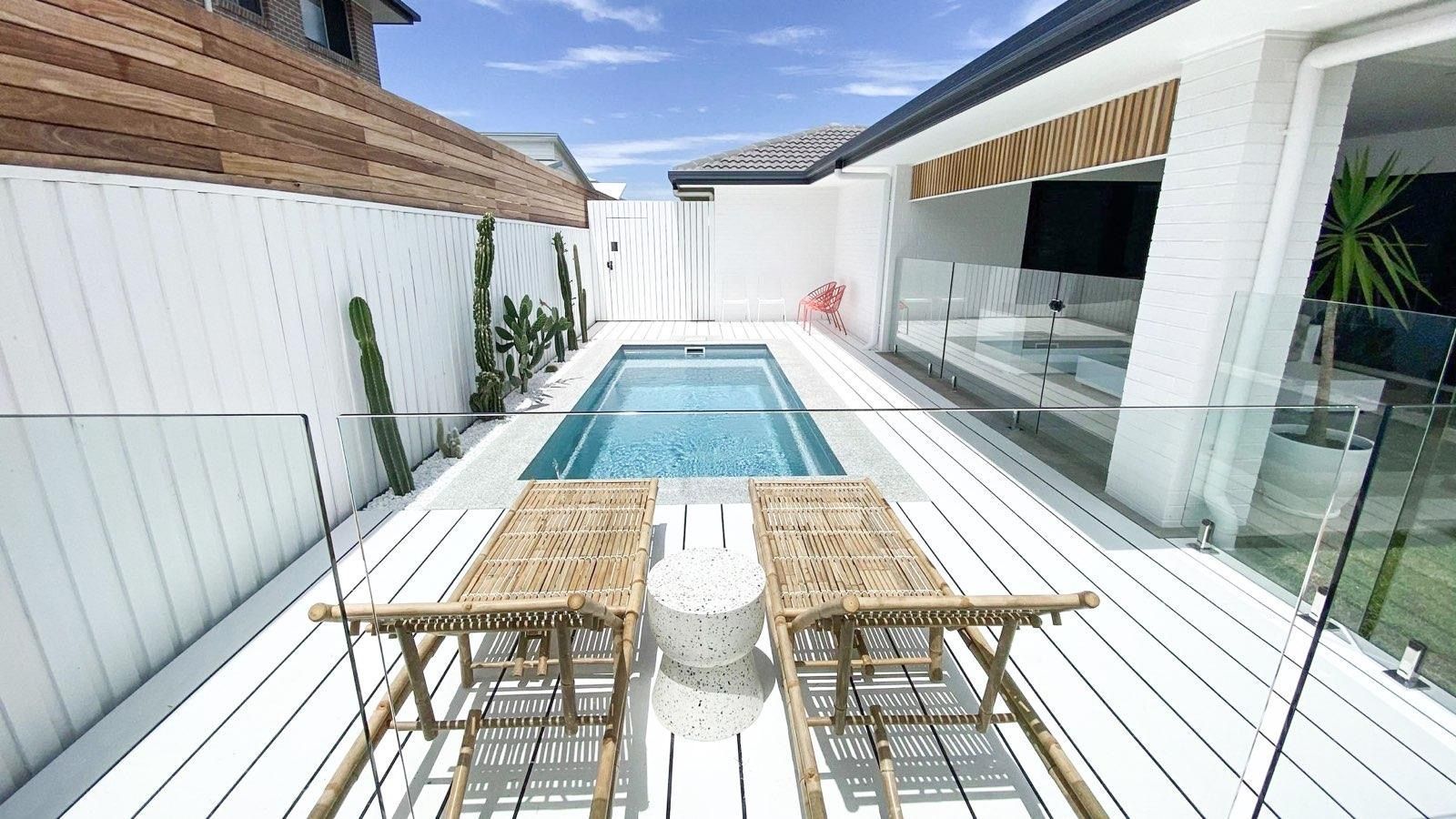 Outdoor pool area with white deck, lounge chairs, and glass fencing — Evoke Pools In Lennox Head, NSW