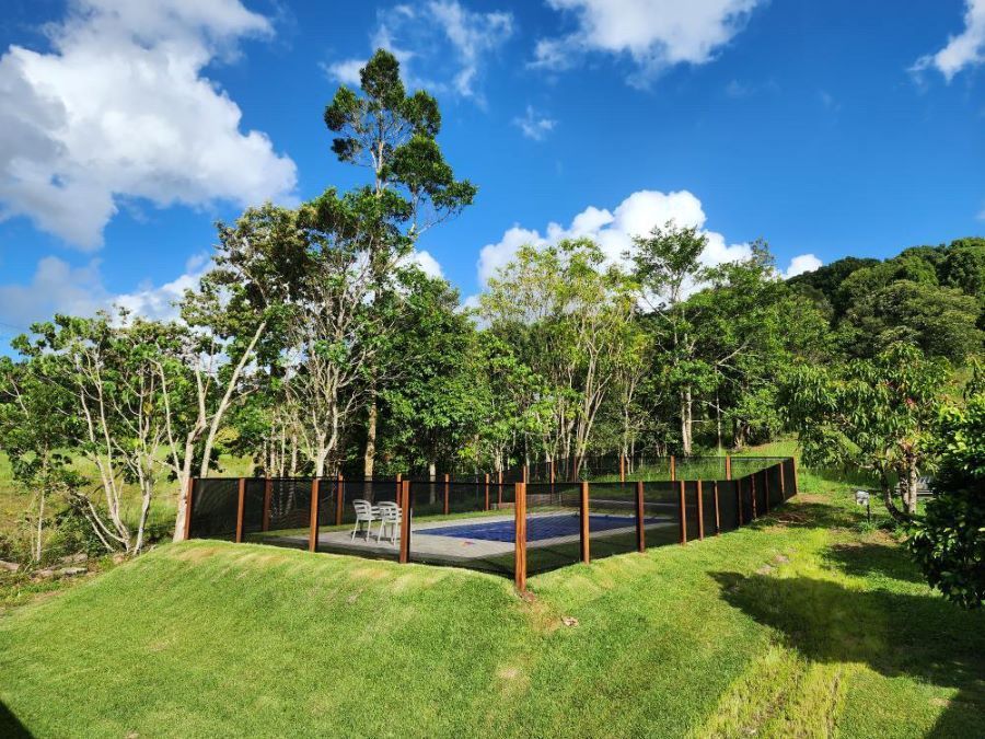 A fence surrounds a swimming pool surrounded by trees