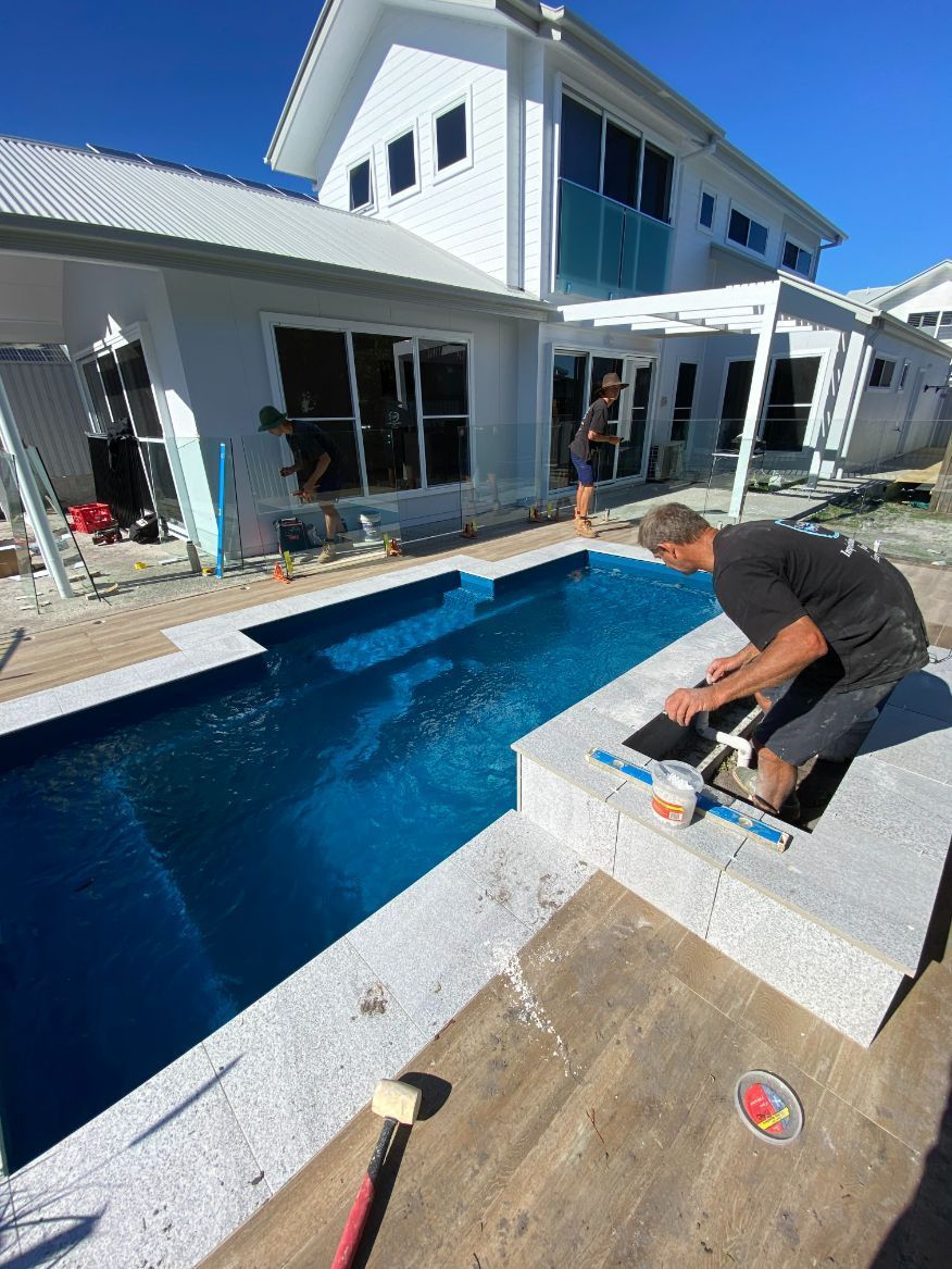 A man is working on a swimming pool in front of a house.