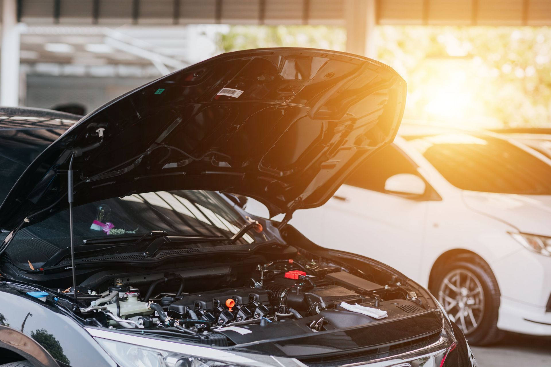 Car with open hood in a garage; engine visible.