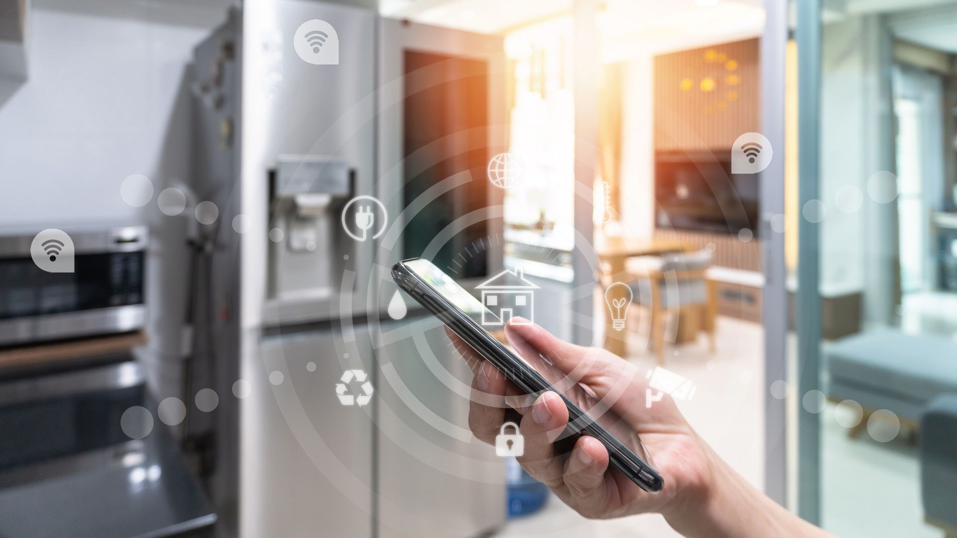 Hand holding phone in kitchen, interacting with smart home icons: refrigerator, lights, lock.