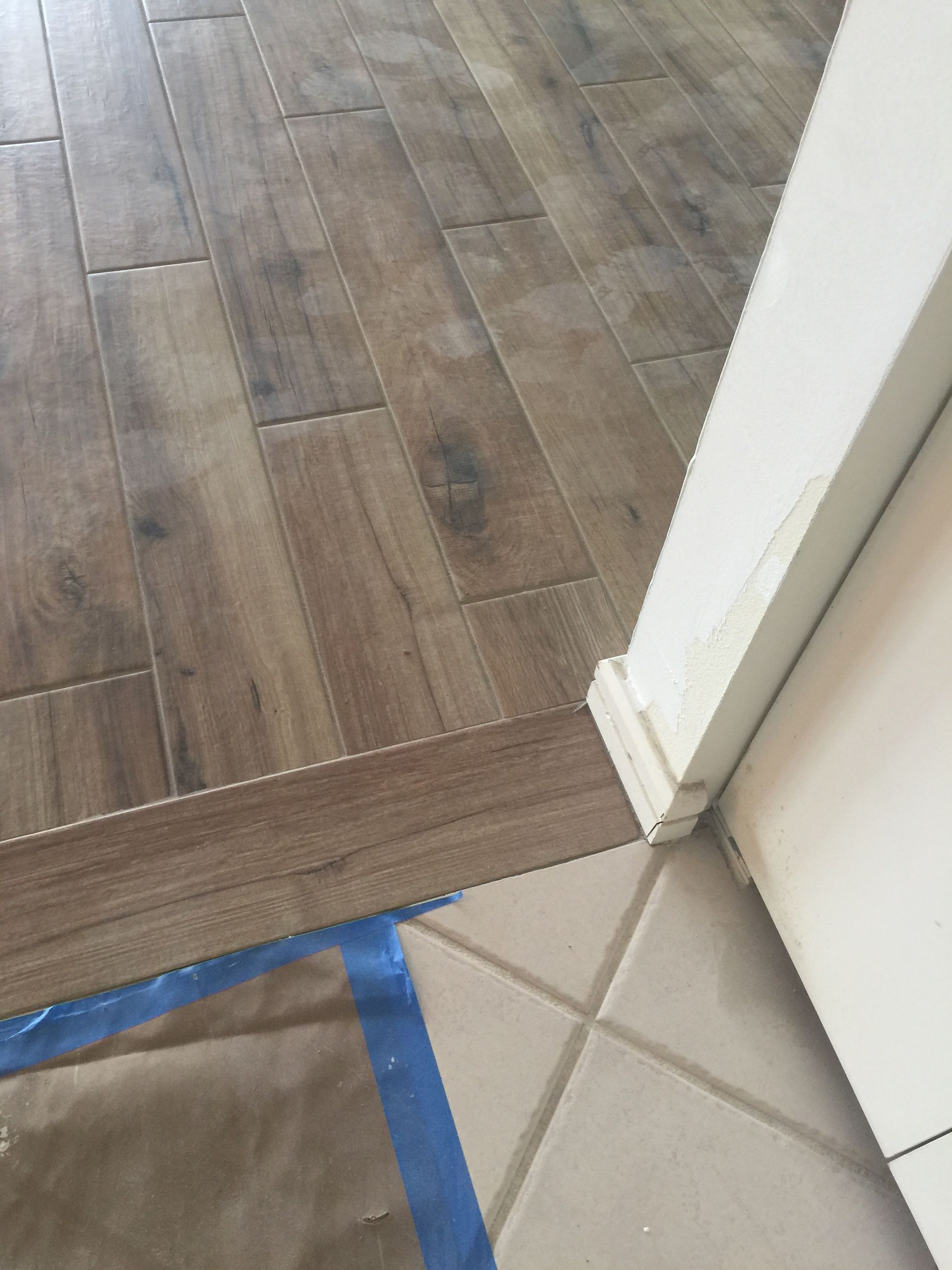 A close up of a wooden floor next to a tile floor.