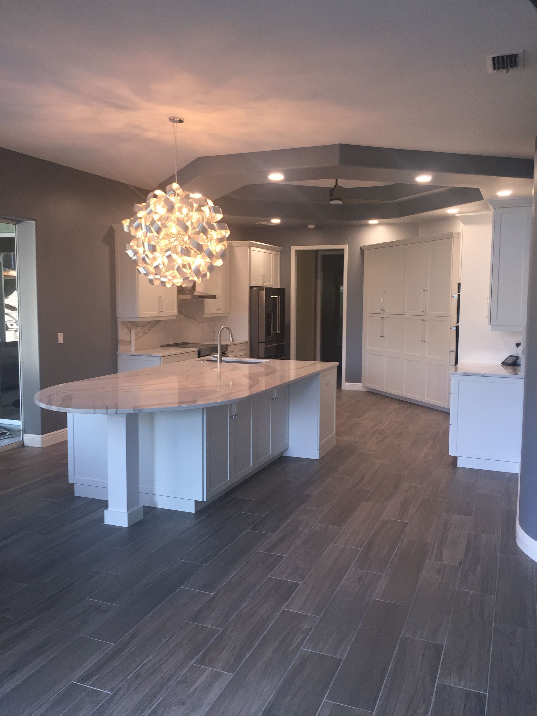 A kitchen with a large island and a chandelier hanging from the ceiling