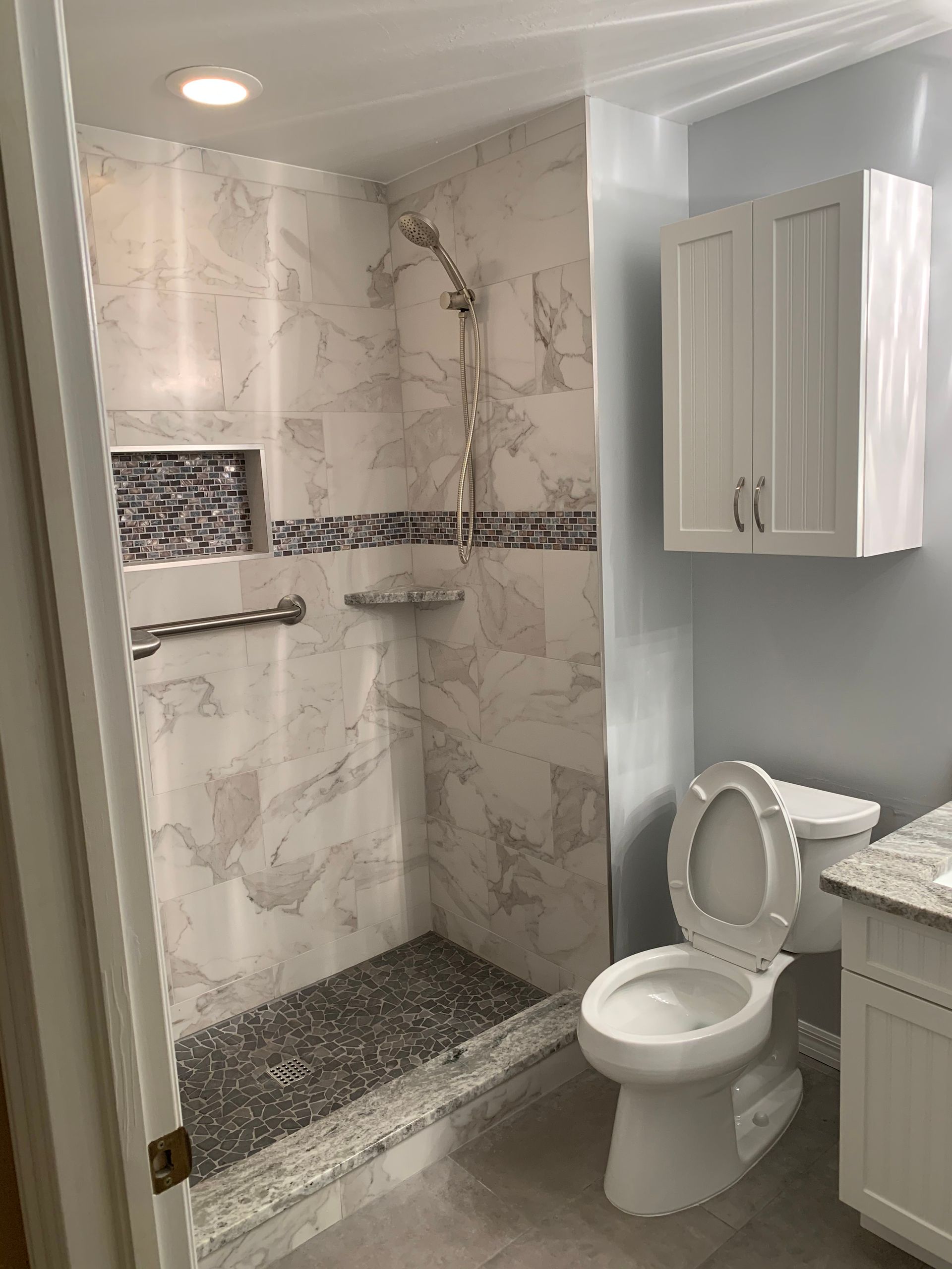 A bathroom with a toilet , sink and shower.