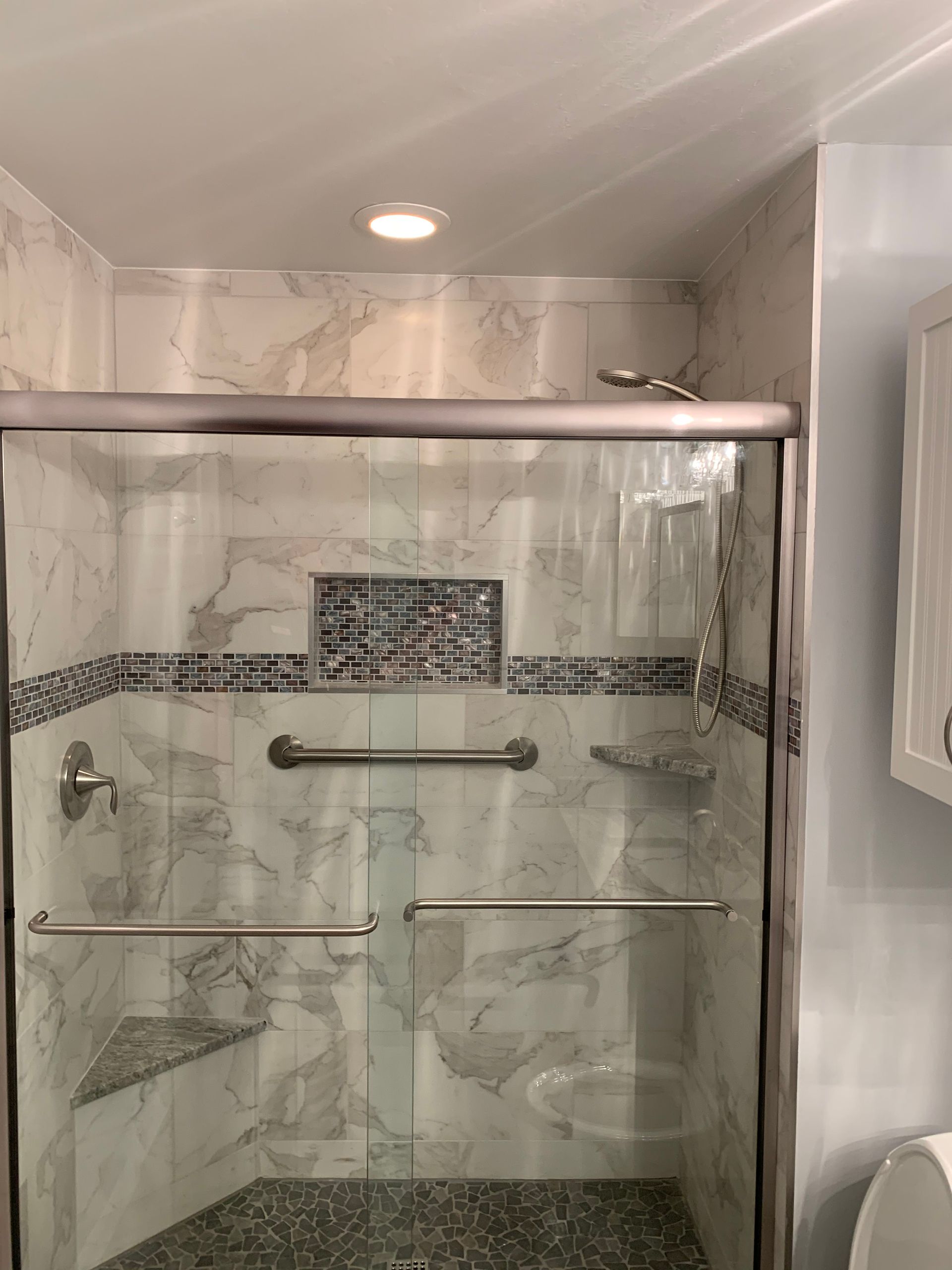 A bathroom with a sliding glass shower door and a toilet.