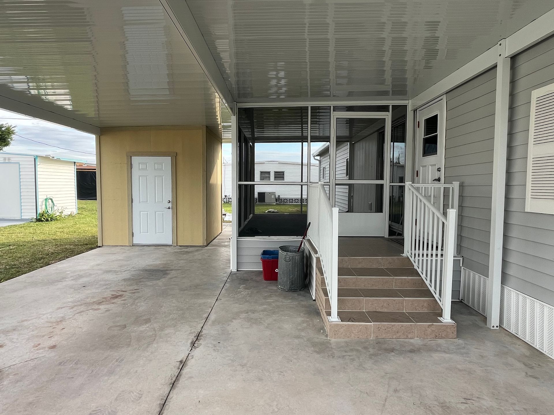 A mobile home with a screened in porch and stairs.