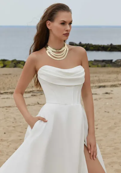 Woman in a white dress with a tulle collar, arms raised, wearing earrings, looking left.