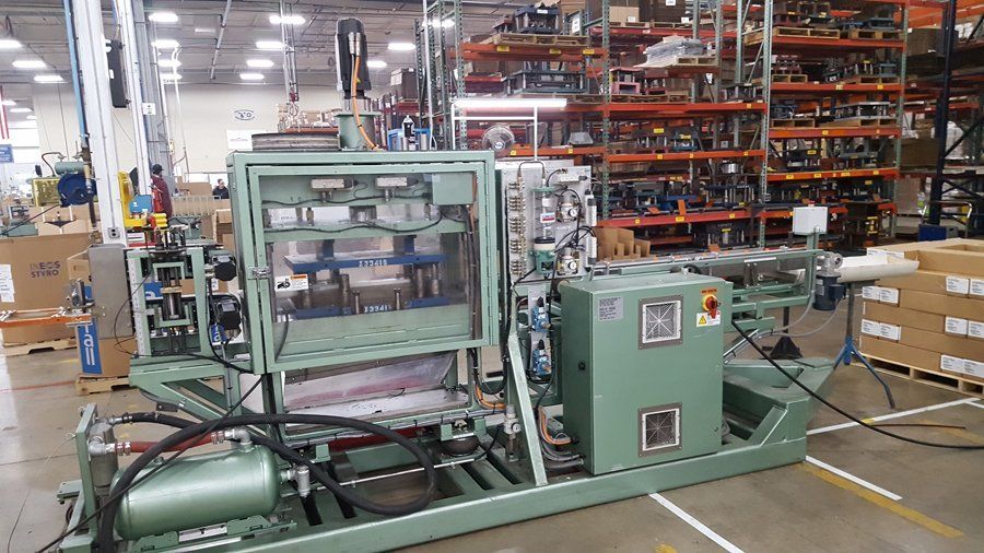 A green machine is sitting in a warehouse.