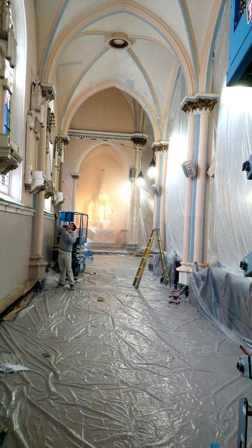A church is being painted and covered in plastic.