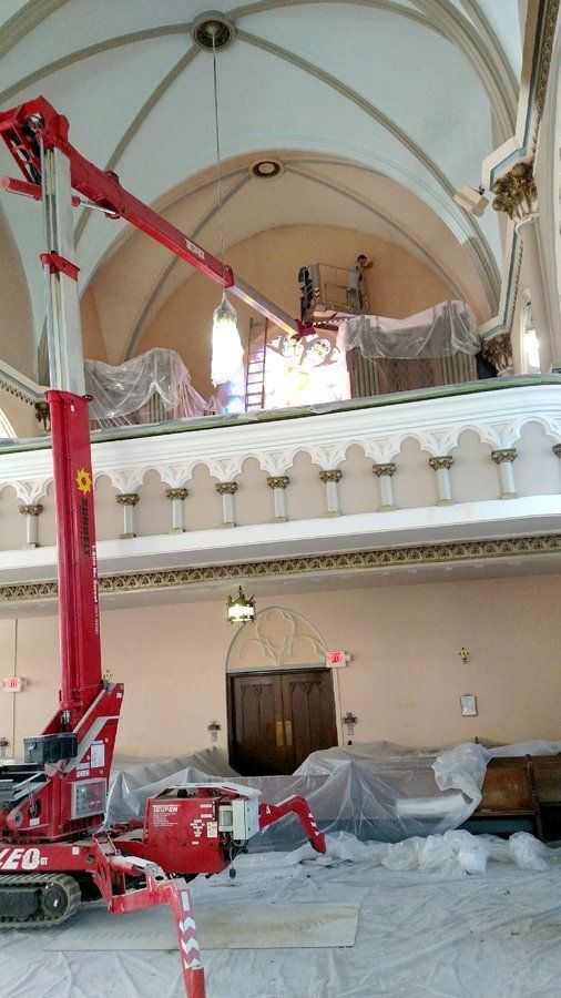 A red crane is working on the ceiling of a building.