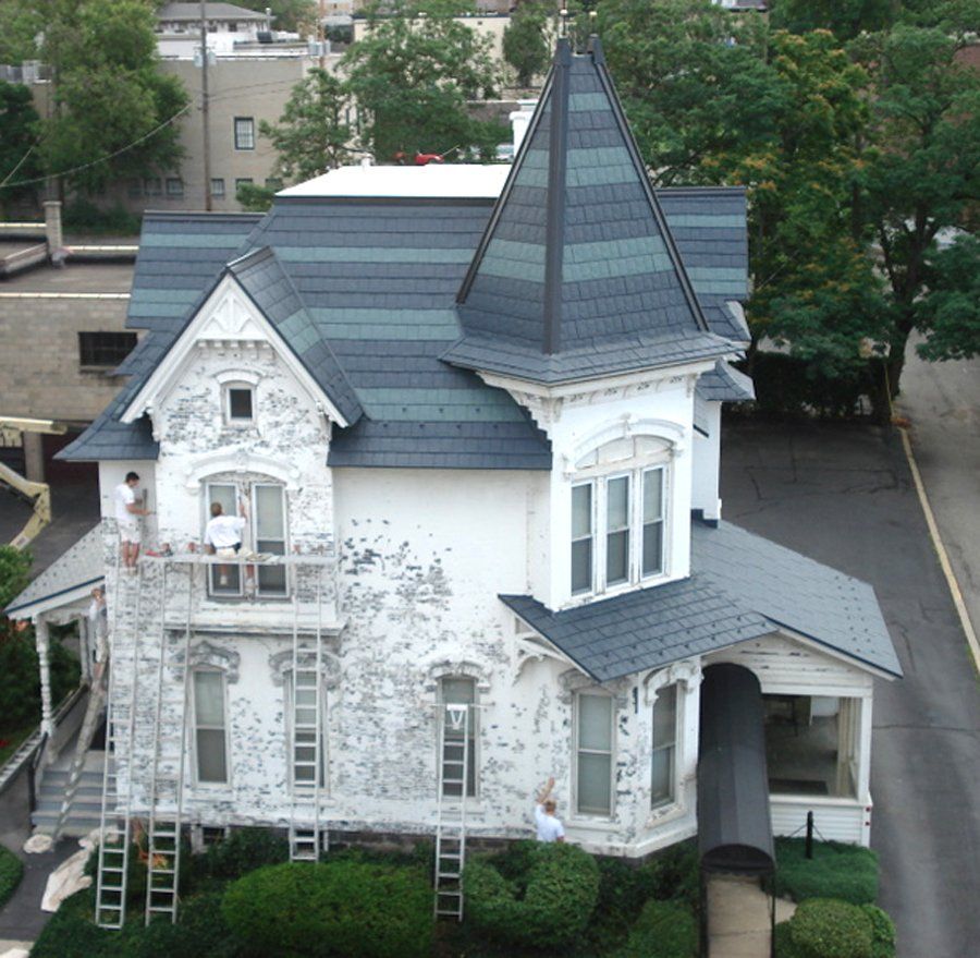 A white house with a black roof is being painted