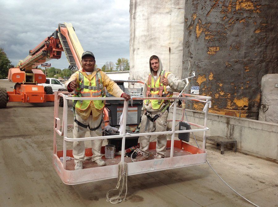 Two construction workers are standing in a bucket.