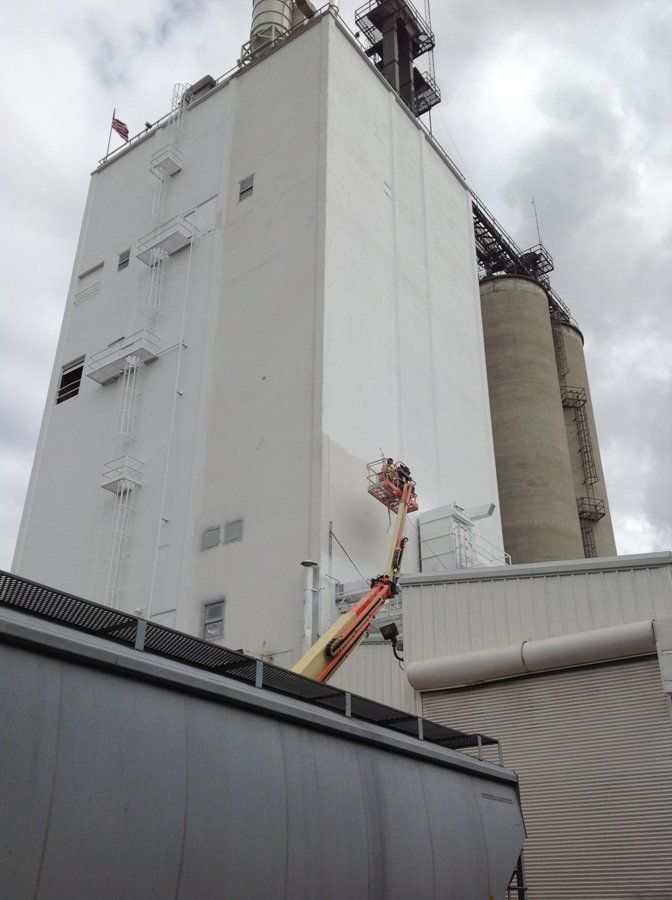 A large white building with a crane in front of it.