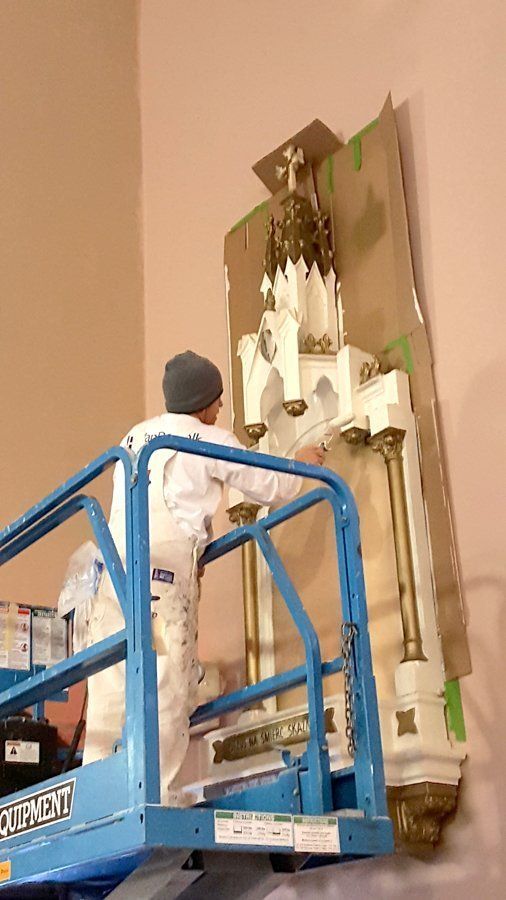 A man is painting a statue on a lift.