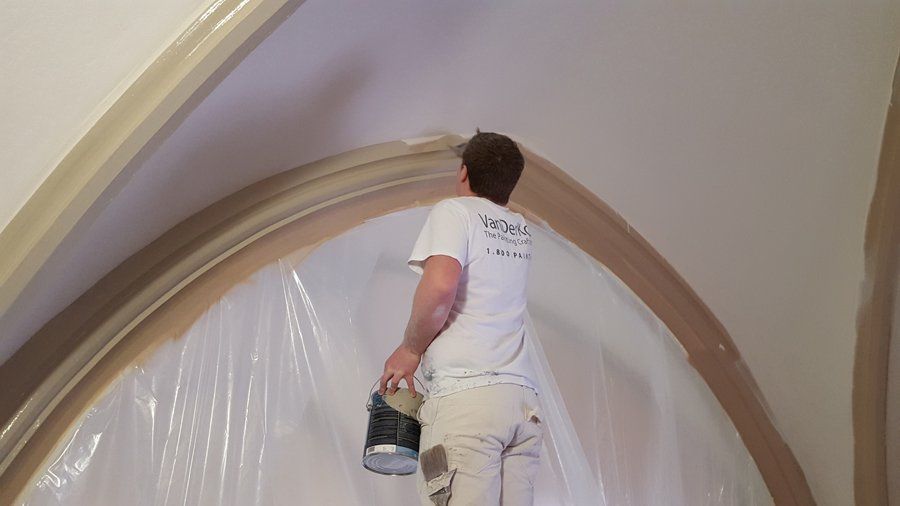 A man is painting a wall with a can of paint.