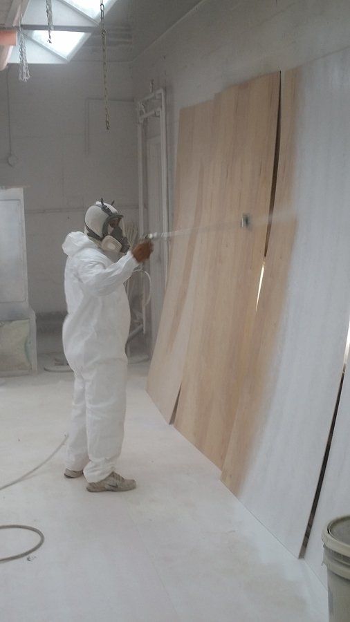 A man in a protective suit is spray painting a wall.